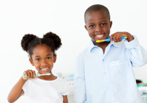 Two smiling children holding toothbrushes, promoting healthy habits and dental insurance benefits in Fair Lawn, NJ.